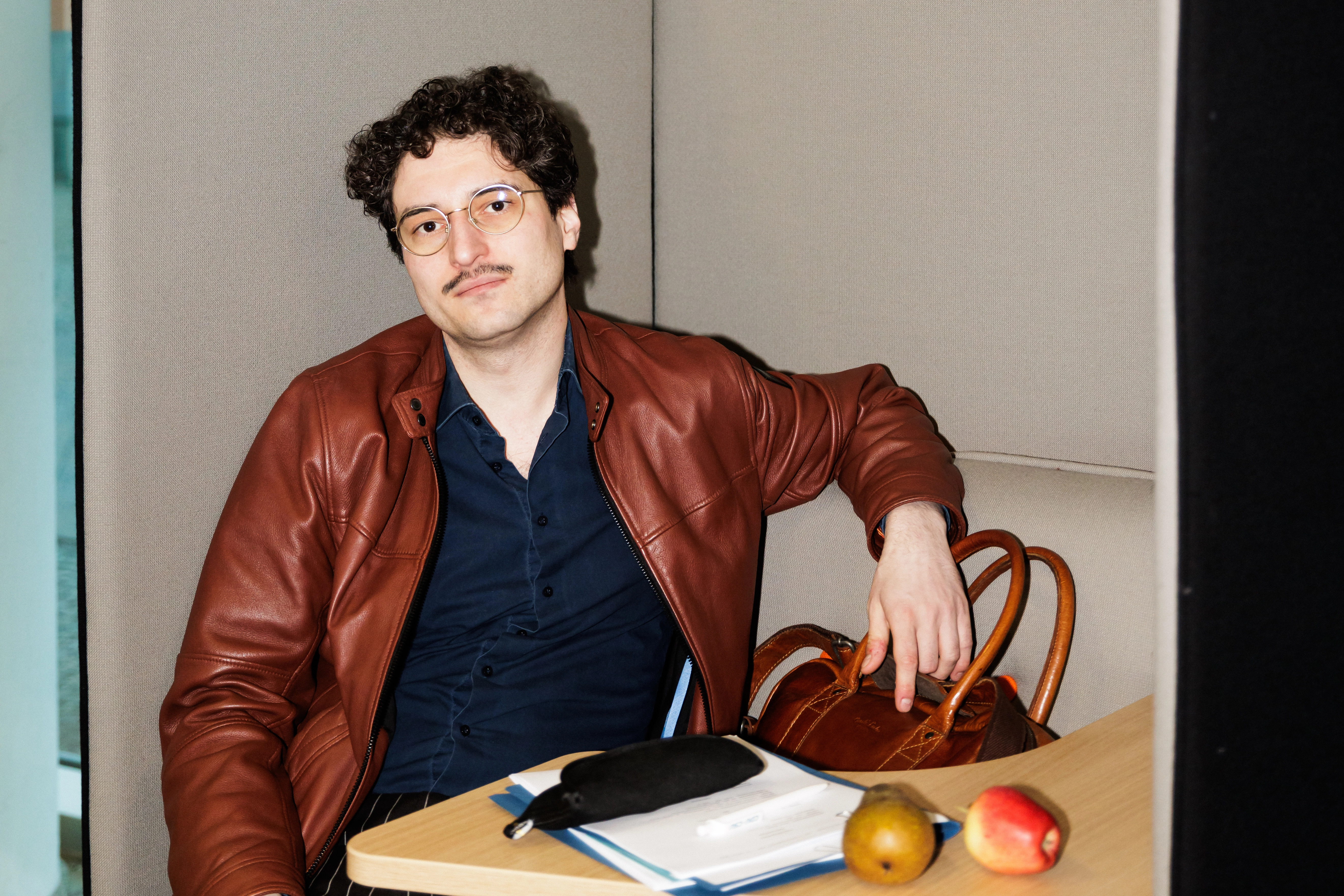 Patrick Pehl in einer braunen Lederjacke mit zwei Äpfeln und Unterlagen auf Papier im Konrad-Adenauer-Haus in Berlin.